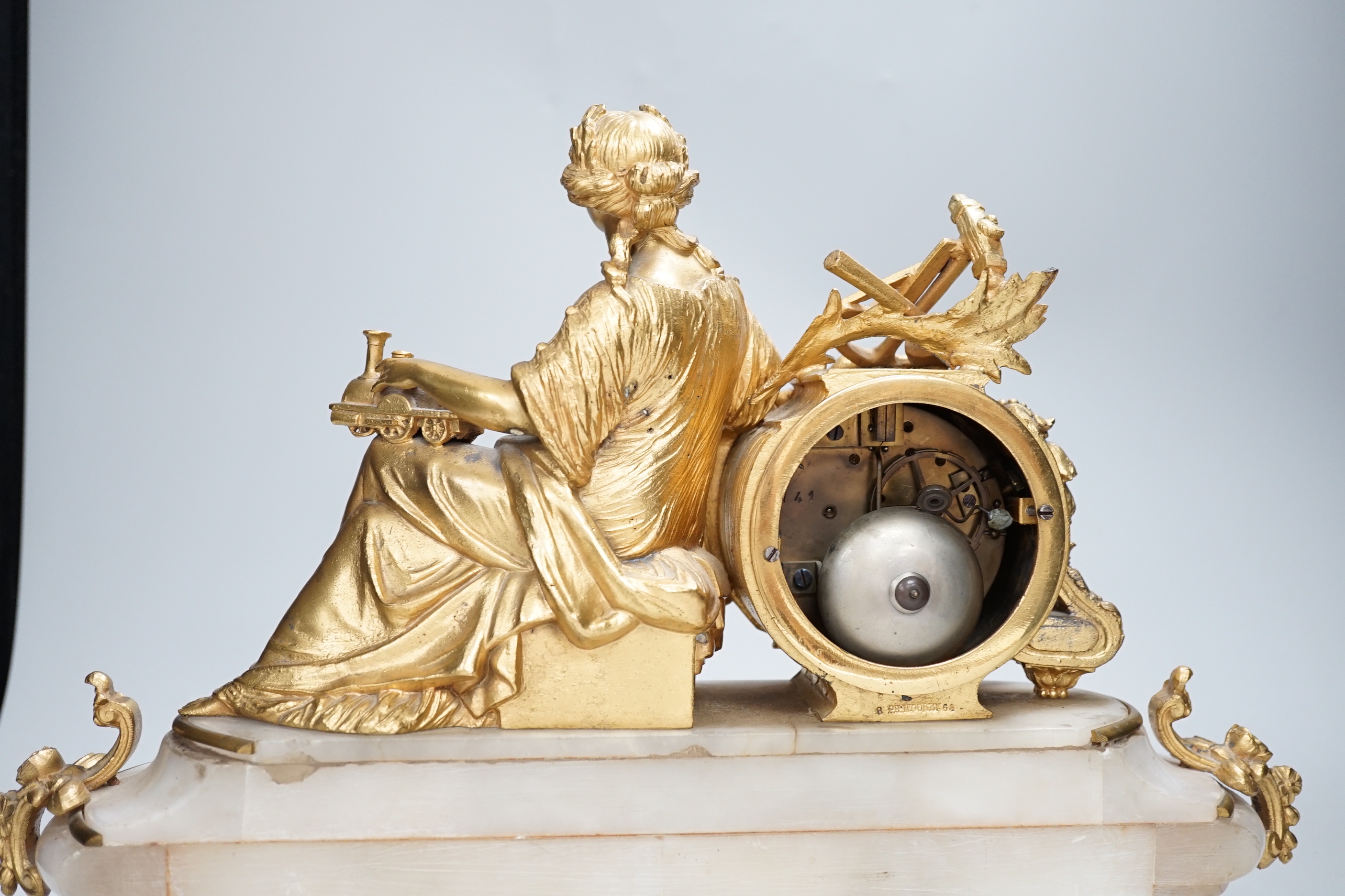 A late 19th century French gilt metal and onyx clock mounted with the figure of Industry holding a locomotive, 42cm wide